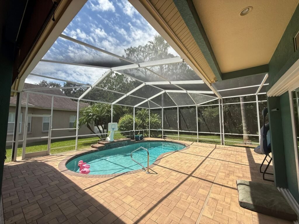 Pool enclosure installation in Spring Hill, FL covering residential pool and paved patio area